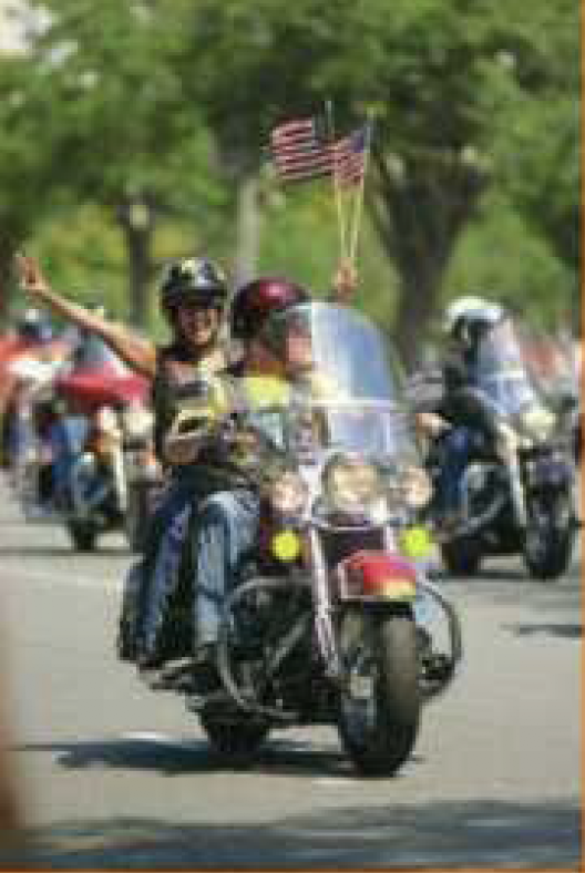 riders holding american flags and showing the peace sign